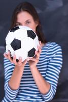 woman holding a soccer ball in front of chalk drawing board photo