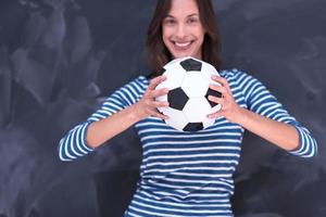 woman holding a soccer ball in front of chalk drawing board photo