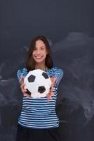 mujer sosteniendo una pelota de fútbol frente a un tablero de dibujo de tiza foto