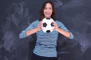 mujer sosteniendo una pelota de fútbol frente a un tablero de dibujo de tiza foto