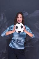 mujer sosteniendo una pelota de fútbol frente a un tablero de dibujo de tiza foto