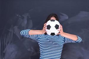 woman holding a soccer ball in front of chalk drawing board photo