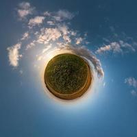 Little planet transformation of spherical panorama 360 degrees. Spherical abstract aerial view in field with awesome beautiful clouds. Curvature of space. photo