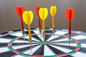 Red and yellow dart arrows hitting in the target center of dartboard. Success hitting target aim goal achievement concept photo