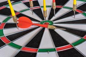 Red and yellow dart arrows hitting in the target center of dartboard. Success hitting target aim goal achievement concept photo