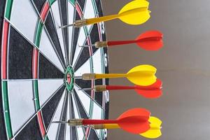 Red and yellow dart arrows hitting in the target center of dartboard. Success hitting target aim goal achievement concept photo