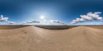 vista de ángulo de 360 grados de panorama hdri esférico completo sin costuras en camino de grava entre campos a principios del día de primavera con sol en cielo despejado con halo en proyección equirectangular, listo para contenido vr ar foto