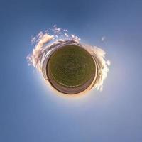 Little planet transformation of spherical panorama 360 degrees. Spherical abstract aerial view in field with awesome beautiful clouds. Curvature of space. photo