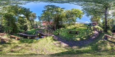 vista de ángulo de 360 grados de panorama hdri esférico completo sin costuras entre arbustos y árboles de lugar de descanso junto al antiguo molino y río angosto en proyección equirectangular, contenido de realidad virtual vr listo foto