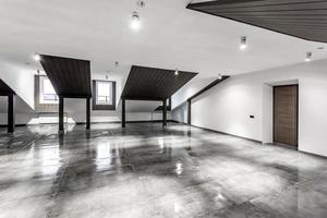 interior vacío de la habitación de buhardilla sin amueblar con columnas de madera y suelo de hormigón húmedo en el nivel del techo en color negro y de estilo completo foto