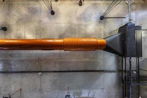 mirando hacia el techo de hormigón gris con manchas halógenas y lámparas edison en la sala de oficinas de loft con aire acondicionado y tubería de ventilación naranja foto