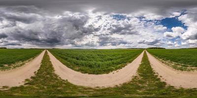 vista de ángulo de 360 grados de panorama hdri esférico completo sin tráfico en camino de grava sin tráfico entre campos con cielo nublado antes de tormenta en proyección equirectangular, listo para contenido de realidad virtual vr ar foto