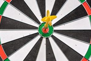 Red and yellow dart arrows hitting in the target center of dartboard. Success hitting target aim goal achievement concept photo