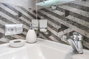 Soap and shampoo dispensers near Ceramic Water tap sink with faucet in expensive loft bathroom or kitchen photo