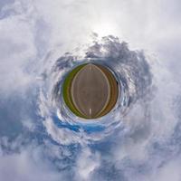 Little planet transformation of spherical panorama 360 degrees. Spherical abstract aerial view in field with awesome beautiful clouds. Curvature of space. photo