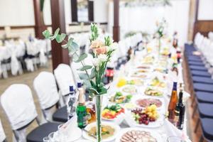 hermosas flores en la elegante mesa de la cena en el día de la boda. decoraciones servidas en la mesa festiva en un fondo borroso foto