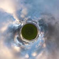 Little planet transformation of spherical panorama 360 degrees. Spherical abstract aerial view in field with awesome beautiful clouds. Curvature of space. photo