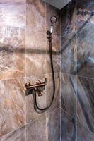 copper water tap sink with faucet in expensive loft bathroom. detail of a corner shower cabin with wall mount shower attachment photo