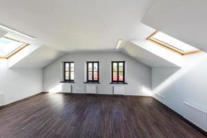 Empty unfurnished loft mansard room interior with wooden columns and wet concrete floor on roof level in white style color with dark parquet photo