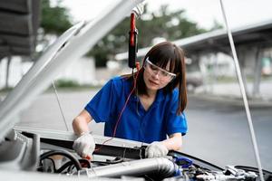 A female car mechanic checking the engine of a car. A mechanic inspects and maintains the engine of a car or vehicle. A female car mechanic checking the engine of a car. car mechanic concept photo