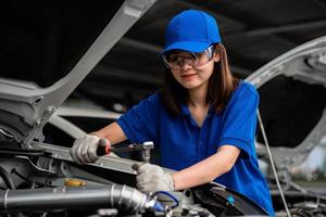 concepto de reparación de automóviles. Mecánico de automóviles de mujer asiática con camisa de acuarela en el garaje. feliz mujer mecánica en el centro de reparación de automóviles foto