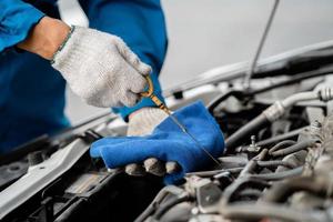 Close-up, a car mechanic checking the oil in a car's engine. Technician inspecting and maintaining the engine of a car or vehicle. Female car mechanic checking car engine photo