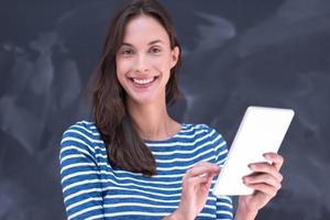 mujer usando una tableta frente a un tablero de dibujo de tiza foto