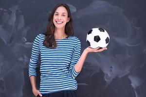 mujer sosteniendo una pelota de fútbol frente a un tablero de dibujo de tiza foto