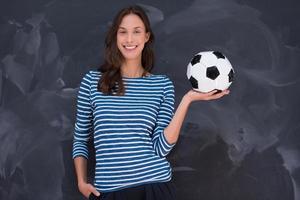 mujer sosteniendo una pelota de fútbol frente a un tablero de dibujo de tiza foto