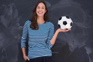 mujer sosteniendo una pelota de fútbol frente a un tablero de dibujo de tiza foto