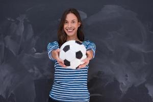 mujer sosteniendo una pelota de fútbol frente a un tablero de dibujo de tiza foto