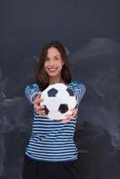 mujer sosteniendo una pelota de fútbol frente a un tablero de dibujo de tiza foto