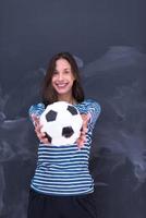 mujer sosteniendo una pelota de fútbol frente a un tablero de dibujo de tiza foto