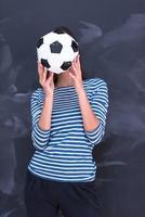 woman holding a soccer ball in front of chalk drawing board photo