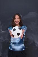 mujer sosteniendo una pelota de fútbol frente a un tablero de dibujo de tiza foto