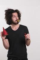 Portrait of a man in party hat blowing in whistle photo