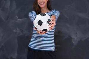 woman holding a soccer ball in front of chalk drawing board photo