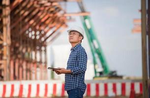 Foreman worker in hardhat at the infrastructure construction site, Construction engineer checking project at the building site, Architect with a digital tablet at a construction site photo