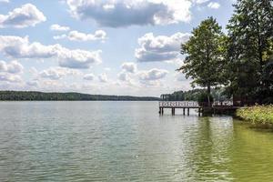 pier on the shore of a large lake in summer day with beautiful clouds.  sky reflection photo