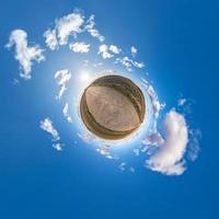 Little planet transformation of spherical panorama 360 degrees. Spherical abstract aerial view in field with awesome beautiful clouds. Curvature of space. photo