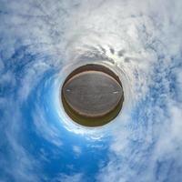 Little planet transformation of spherical panorama 360 degrees. Spherical abstract aerial view in field with awesome beautiful clouds. Curvature of space. photo