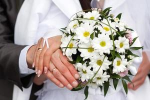 groom embraces the bride with wedding bouquet. rings on the hands of newly-married couple. bride put her hands on the shoulders of the bridegroom. photo