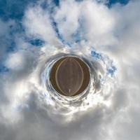 Little planet transformation of spherical panorama 360 degrees. Spherical abstract aerial view in field with awesome beautiful clouds. Curvature of space. photo