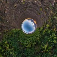 Inversion of little planet transformation of spherical panorama 360 degrees. Spherical abstract aerial view in field with awesome beautiful clouds. Curvature of space. photo