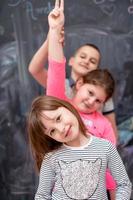 group of kids standing in front of chalkboard photo