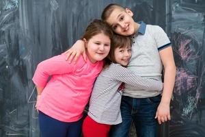 group of kids hugging in front of chalkboard photo