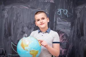 boy using globe of earth in front of chalkboard photo