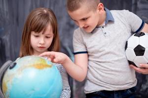 niño y niña usando el globo terráqueo frente a la pizarra foto