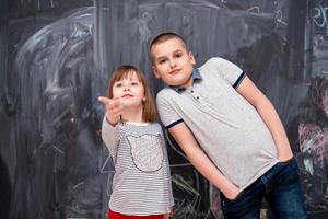 niño y niña parados frente a la pizarra foto