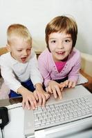 los niños se divierten y juegan en la computadora portátil foto